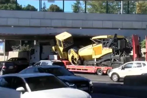 İş makinesi taşıyan tır köprü altına sıkıştı