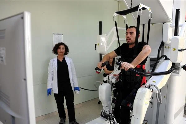 Gribin tetiklediği sendromla felç geçirdi, robotla yürümeye çalışıyor