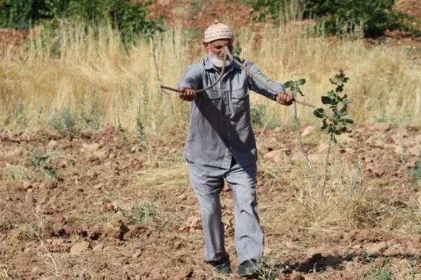 Elinde çubuklarla gezip köyleri suya kavuşturuyor